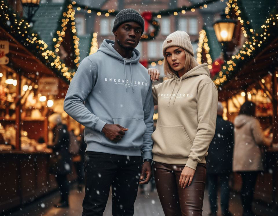 Two people wearing hoodies in a festive outdoor setting with lights and decorations.